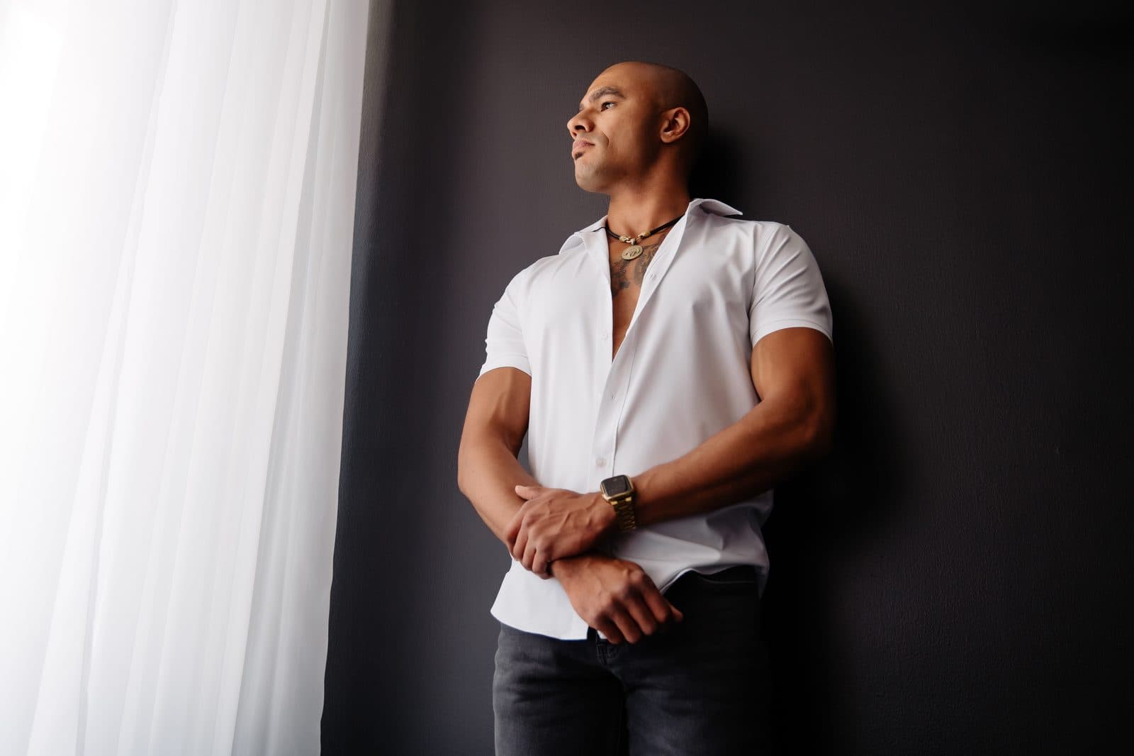 A man in a white shirt stands by the window