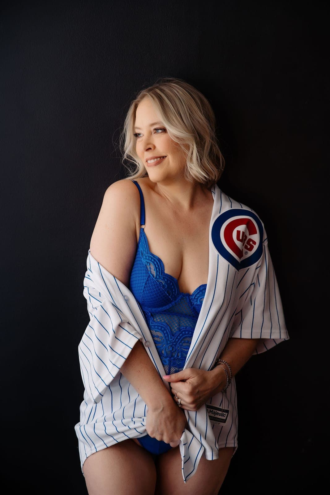 A smiling blonde client in blue lace lingerie wears an open pinstripe baseball jersey
