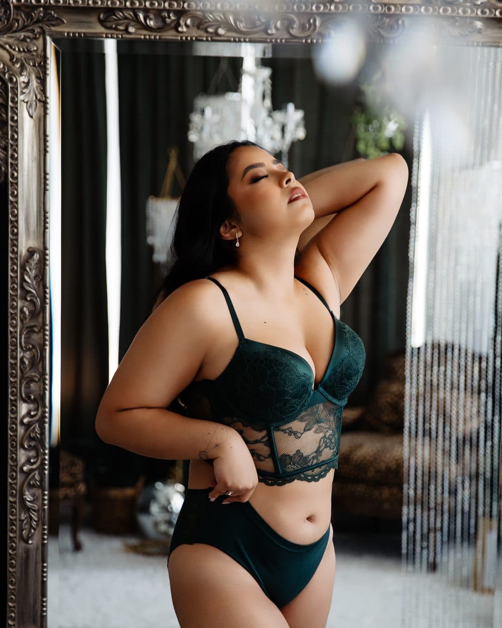 A client in green lace lingerie in front of the tall silver mirror
